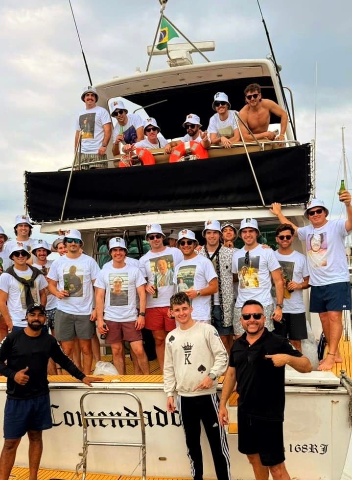 Grupo comemorando a bordo com os morros do Rio ao fundo